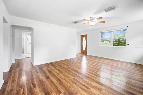 a view of an empty room with wooden floor and a window
