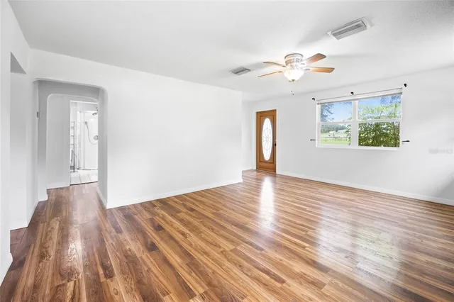 a view of an empty room with wooden floor and a window