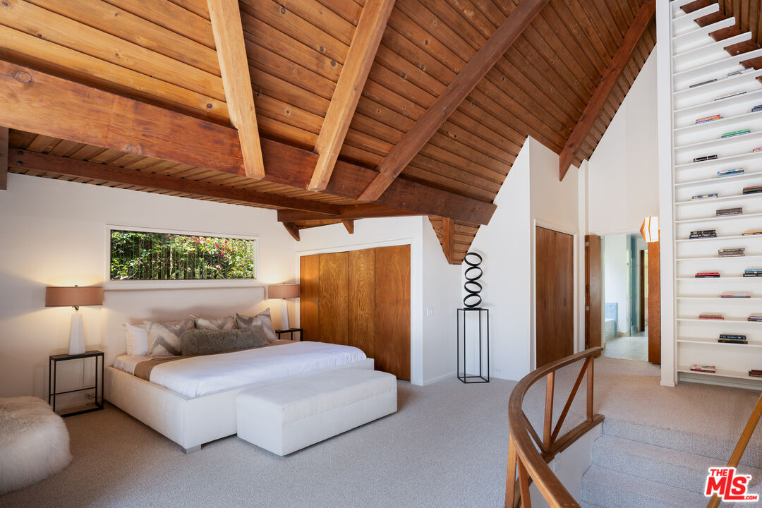 1963 Mandeville Canyon Road Los Angeles, CA 90049 - Photo 29 of 46 a bedroom with a bed and wooden floor