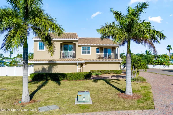 front view of house with a yard and palm trees