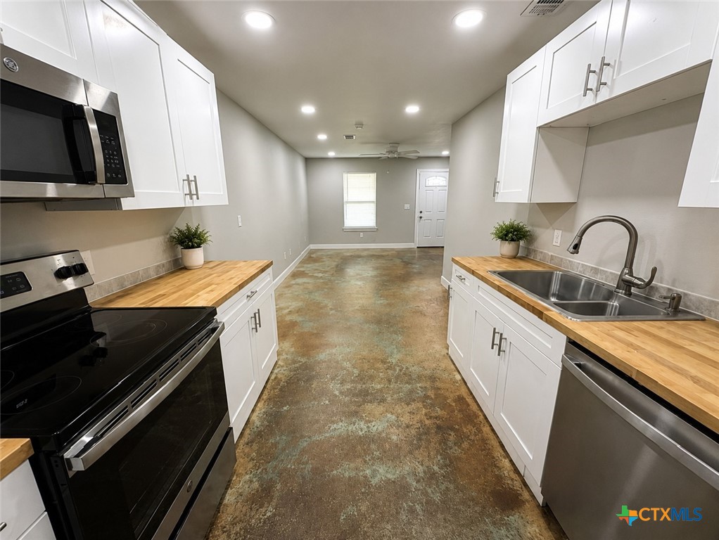 661 West Austin Street, Unit Q Luling, TX 78648 - Photo 2 of 9 a kitchen with kitchen island granite countertop a sink stainless steel appliances and cabinets