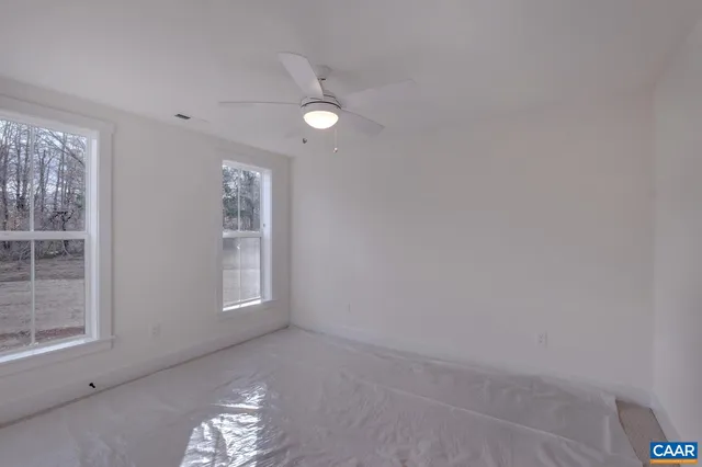 an empty room with windows and chandelier fan