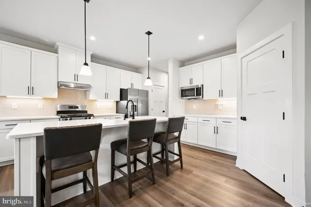 a kitchen with stainless steel appliances a dining table chairs stove microwave and cabinets