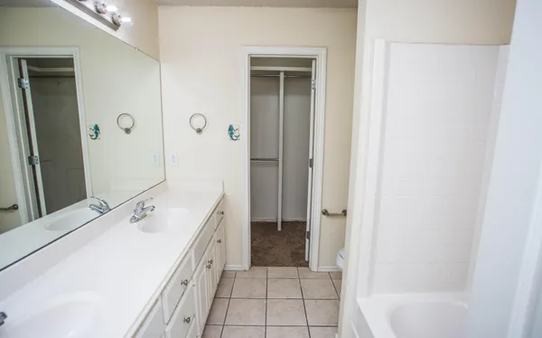 a spacious bathroom with a double vanity sink a mirror and a bathtub