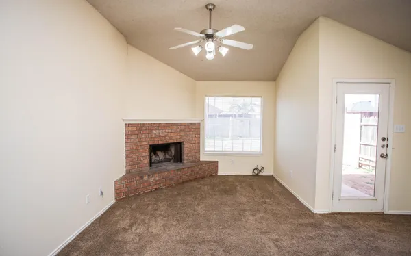 an empty room with chandelier fan and windows