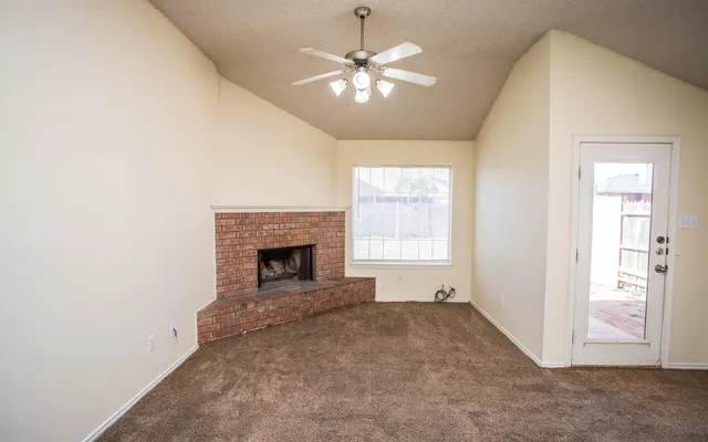 an empty room with chandelier fan and windows