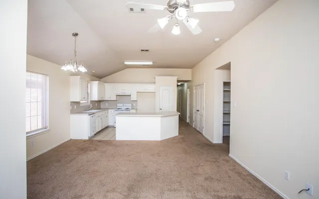a large kitchen with kitchen island white cabinets and chandelier