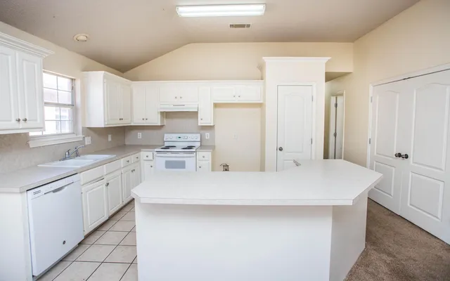 a kitchen with a sink a stove a refrigerator and white cabinets