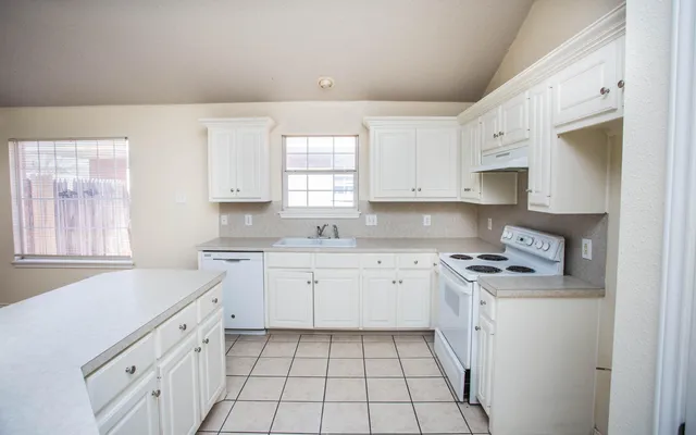 a kitchen with cabinets appliances a sink and a window