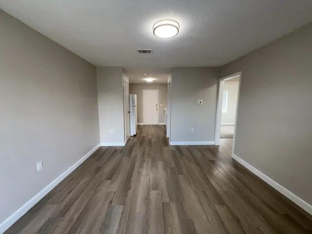 an empty room with wooden floor and windows
