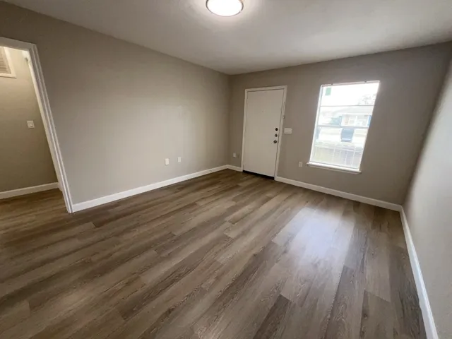 an empty room with wooden floor and windows