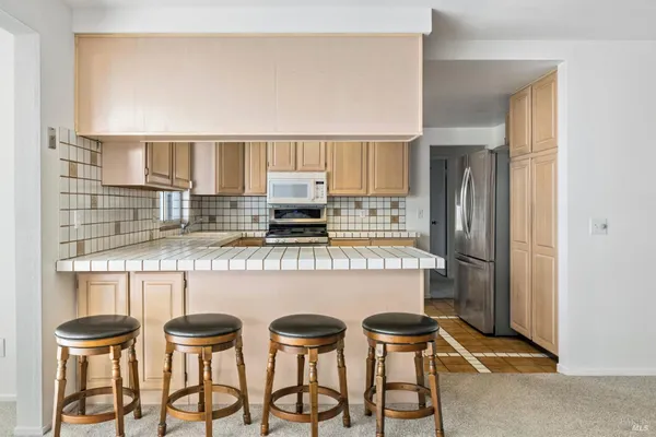 a kitchen with stainless steel appliances a table chairs and a refrigerator