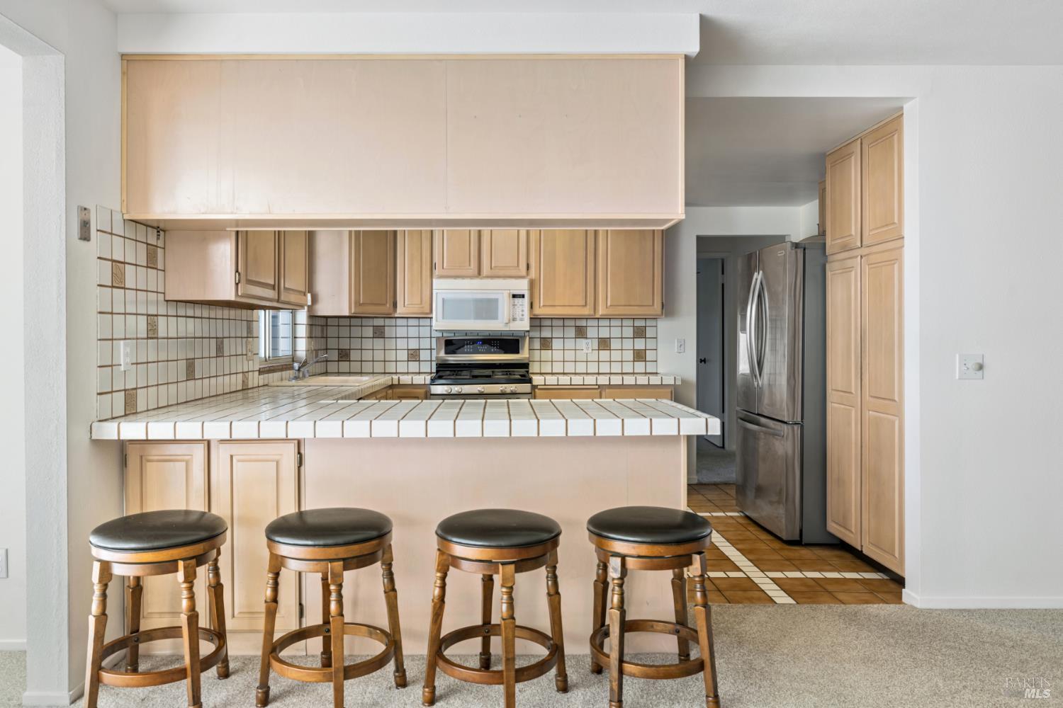 6 Oakhurst Place Santa Rosa, CA 95409 - Photo 16 of 42 a kitchen with stainless steel appliances a table chairs and a refrigerator