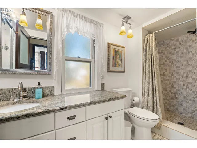 a bathroom with a granite countertop toilet sink and mirror