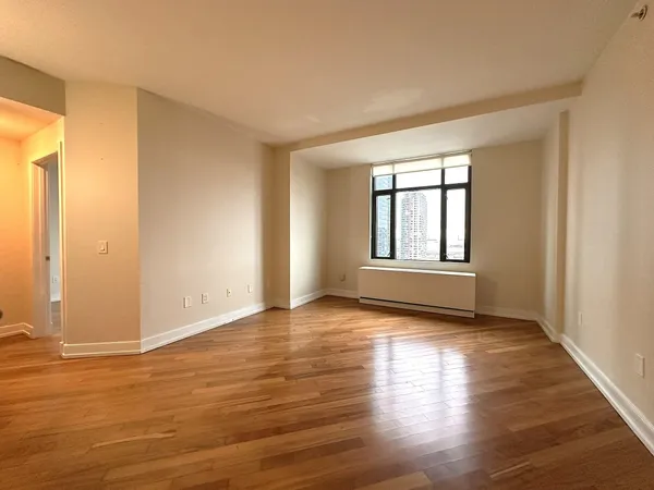 a view of an empty room with wooden floor and a window