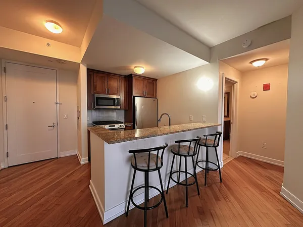 a kitchen with stainless steel appliances a dining table chairs stove refrigerator and microwave