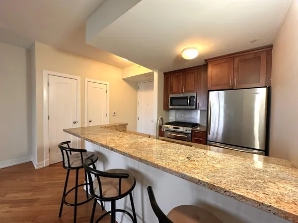 a kitchen with stainless steel appliances granite countertop a table chairs sink refrigerator and microwave