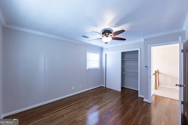 a view of empty room with wooden floor and fan