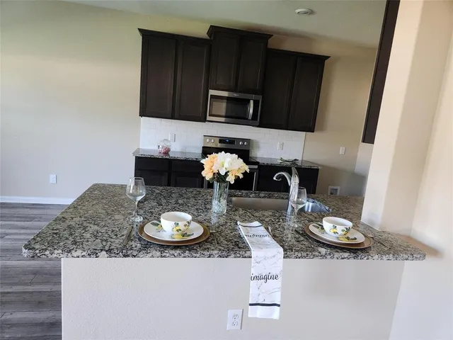 a kitchen with stainless steel appliances granite countertop a sink dishwasher stove top oven and microwave