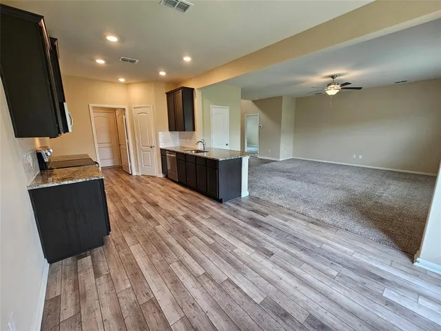 a large kitchen with kitchen island granite countertop a sink and dishwasher a stove with wooden floor