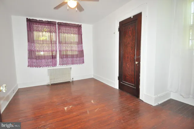 an empty room with a window and a chandelier fan