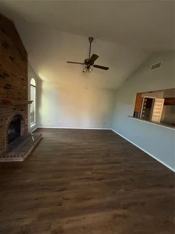 an empty room with wooden floor fireplace and windows