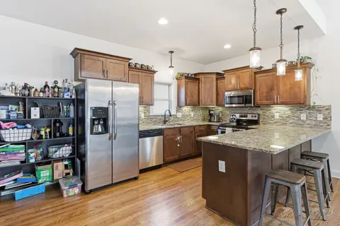 a kitchen with stainless steel appliances granite countertop a refrigerator a stove and a wooden floors