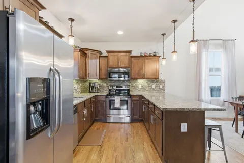 a large kitchen with stainless steel appliances granite countertop a refrigerator a oven and a sink