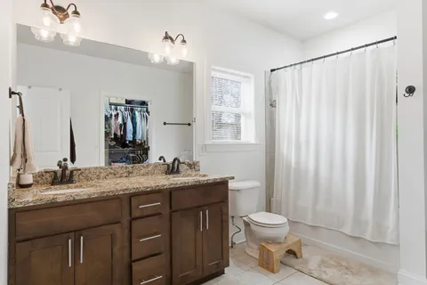 a bathroom with a granite countertop sink toilet a mirror and shower