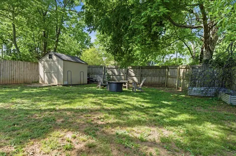 a view of a backyard with large trees and wooden fence