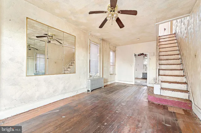 a view of a livingroom with wooden floor and a ceiling fan