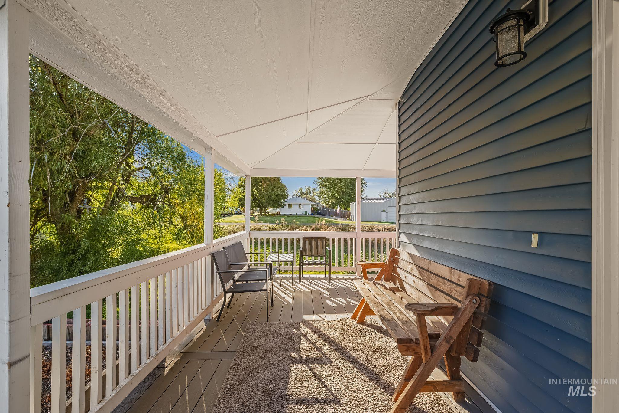 Covered porch with white railings, wood-finish decking, and blue horizontal siding