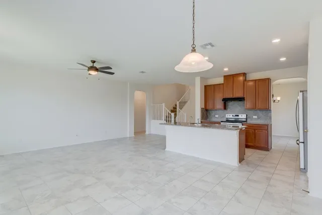 a kitchen with stainless steel appliances granite countertop a sink a stove a refrigerator and a granite counter tops