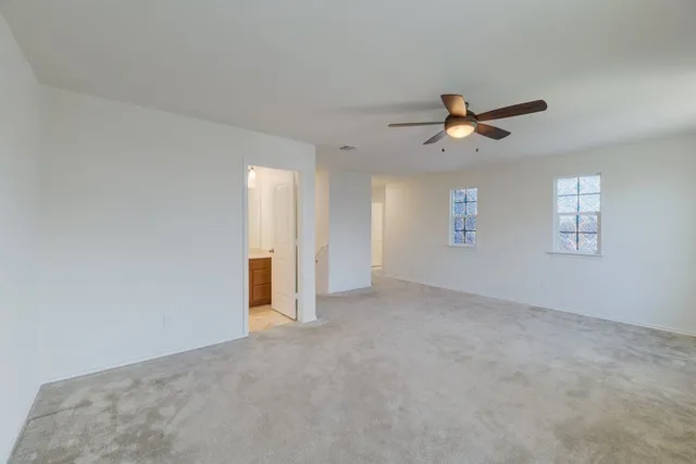 a view of a big room with windows and chandelier fan