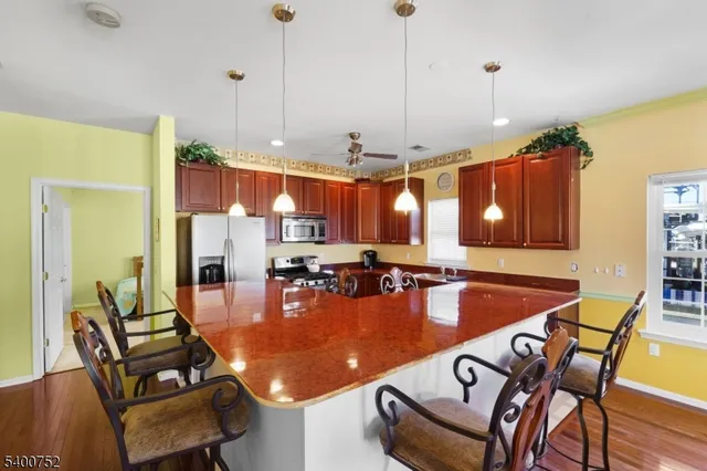 a kitchen with granite countertop a stove a sink a refrigerator wooden floor cabinets and dining table