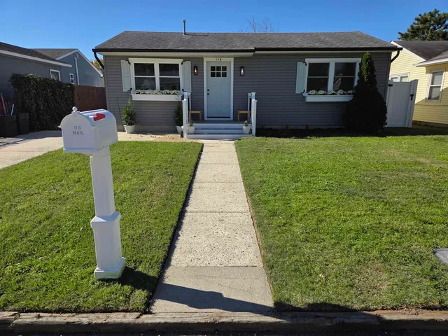 a front view of a house with a yard and potted plants