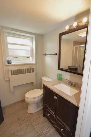 a bathroom with a granite countertop toilet sink and mirror