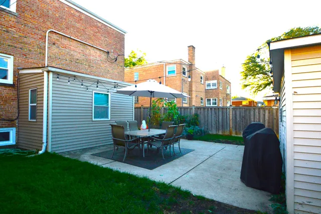 a view of a patio with table and chairs and wooden fence
