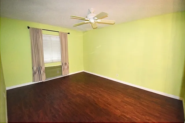 a view of an empty room with a window and a ceiling fan