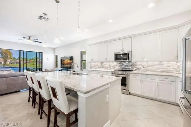 a kitchen with stainless steel appliances kitchen island granite countertop a table chairs and a refrigerator