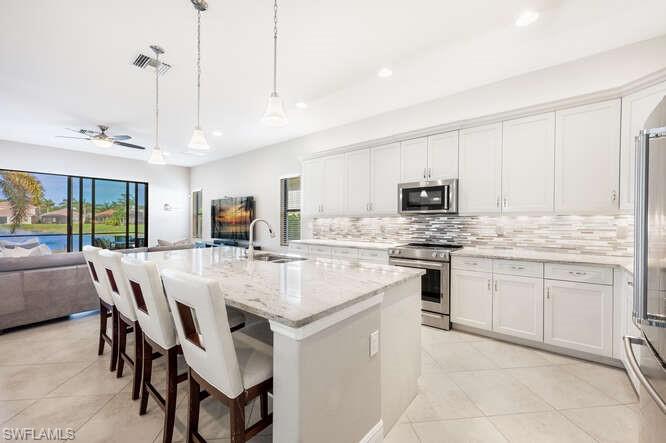 a kitchen with stainless steel appliances kitchen island granite countertop a table chairs and a refrigerator