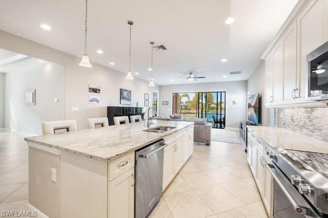 1641 Serrano Circle Naples, FL 34105 - Photo 13 of 50 a large kitchen with kitchen island a stove a sink a center island and living room view