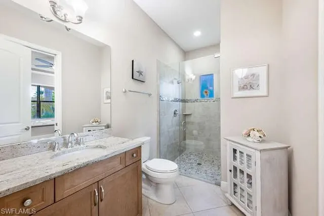 a bathroom with a granite countertop sink a toilet a shower and a mirror