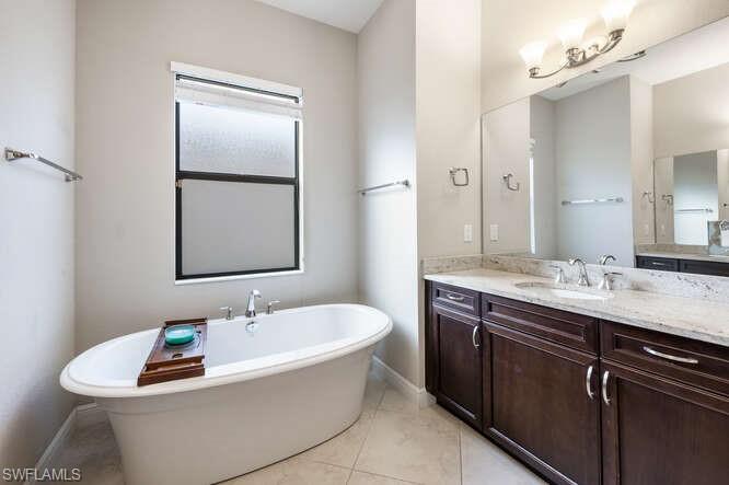 1641 Serrano Circle Naples, FL 34105 - Photo 26 of 50 a bathroom with a tub a sink and mirror