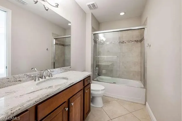a bathroom with a granite countertop sink a toilet a mirror and shower