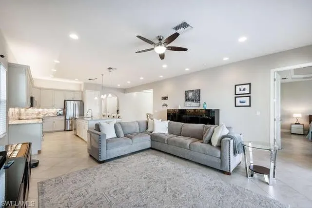 a living room with furniture kitchen view and a chandelier