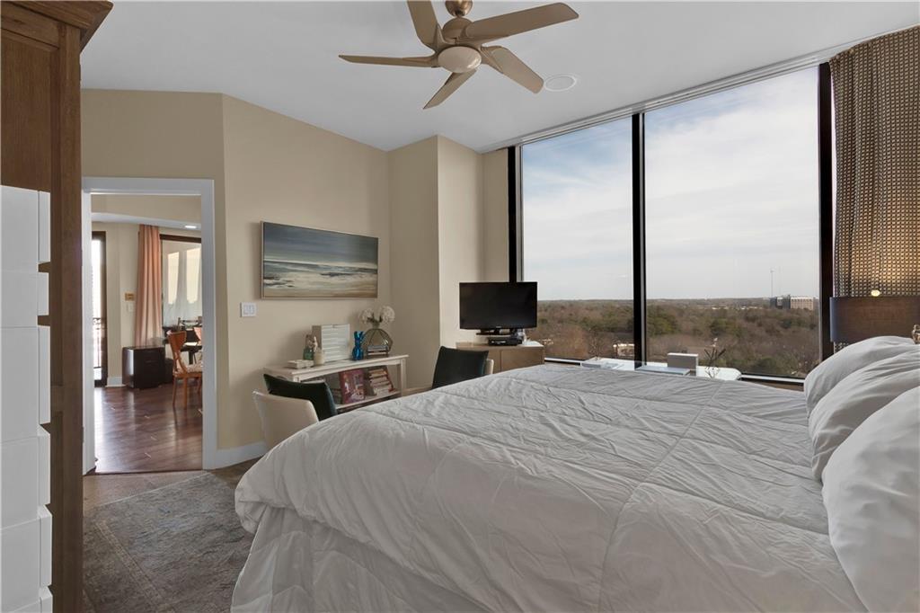 2828 Peachtree Road Northwest, Unit 1402 Atlanta, GA 30305 - Photo 19 of 23 a bedroom with a bed a chandelier with a flat screen tv and a large window