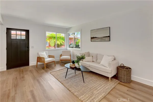 a living room with furniture and a potted plant on table with wooden floor