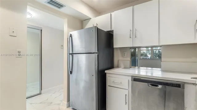 a kitchen with a refrigerator and white cabinets
