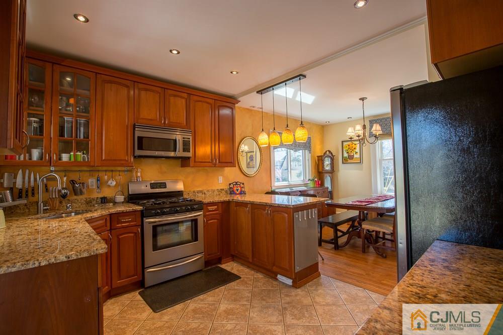 60 Rector Street Metuchen, NJ 08840 - Photo 5 of 25 a kitchen with stainless steel appliances granite countertop a stove top oven a sink dishwasher and wooden cabinets